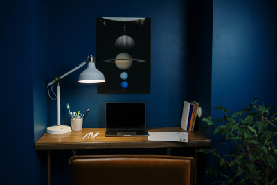 A desk with a laptop and a lamp on it