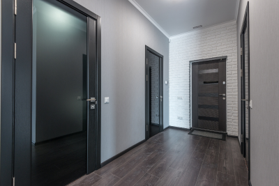 A long hallway with two black doors and a white brick wall